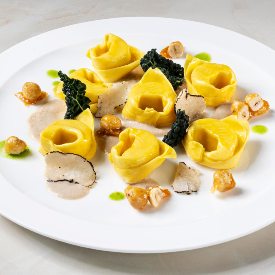 Balanzoni de Parmigiano con jugo de col rizada, avellanas y trufa negra