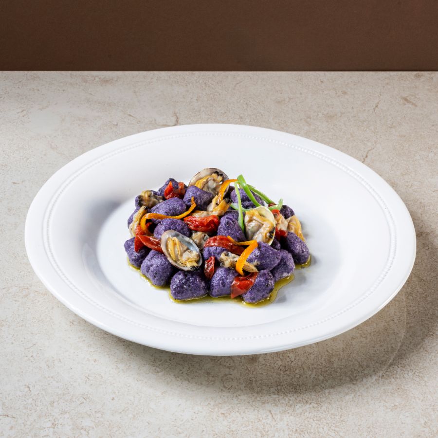 Mammoli de pommes de terre violettes Vitelotte avec des palourdes fraîches, des tomates cerises confites et du zeste d&rsquo;orange.