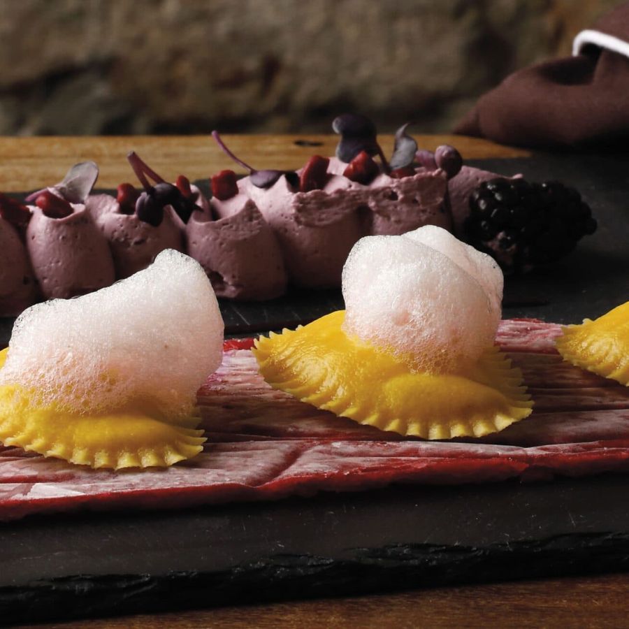 Raviolotti with polenta and Montasio DOP cheese, raspberry carpaccio, whipped berry ganache, rose air