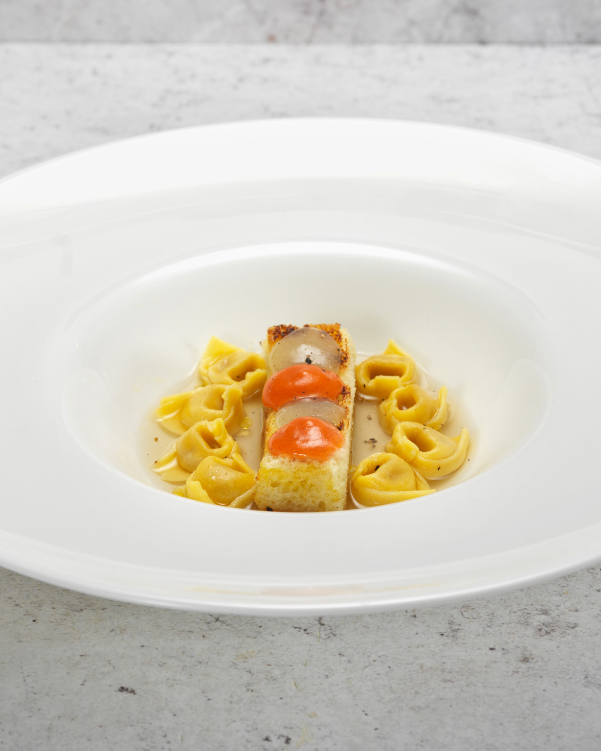 K107_Tortellini-alla-moda-di-Bologna-con-brodo-di-parmigiano-porro-bruciato-e-crostone-di-pane-con-gel-di-sedano-e-pomodoro